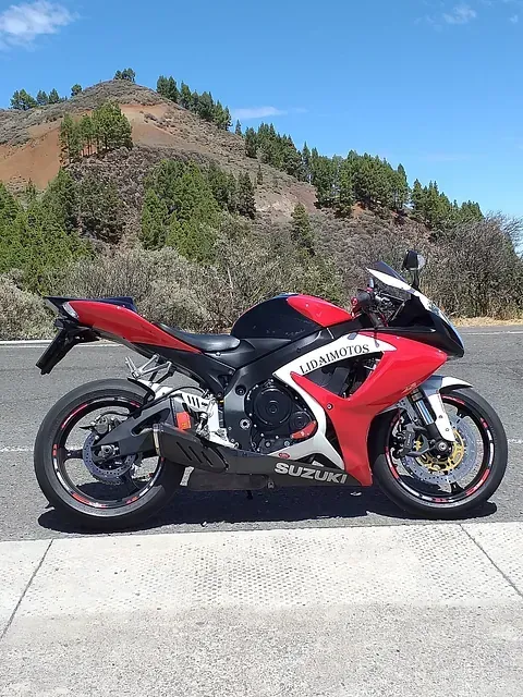 Una motocicleta Suzuki roja y negra está estacionada al costado de la carretera.