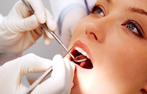 Una mujer está siendo examinada por un dentista.