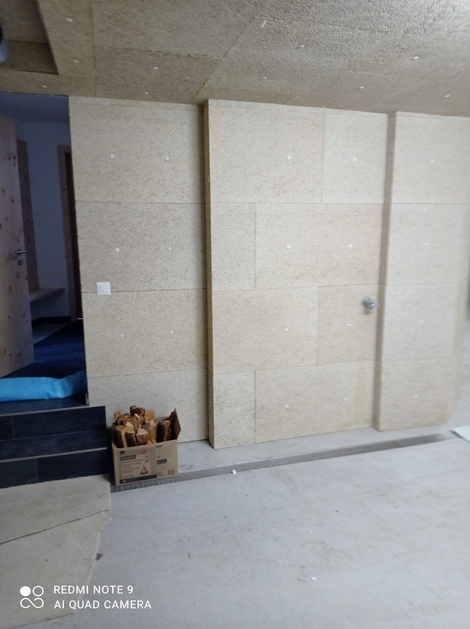 Die Innenwand ist mit hellen, rechteckigen Schalldämmplatten verkleidet und verfügt über eine Türöffnung.