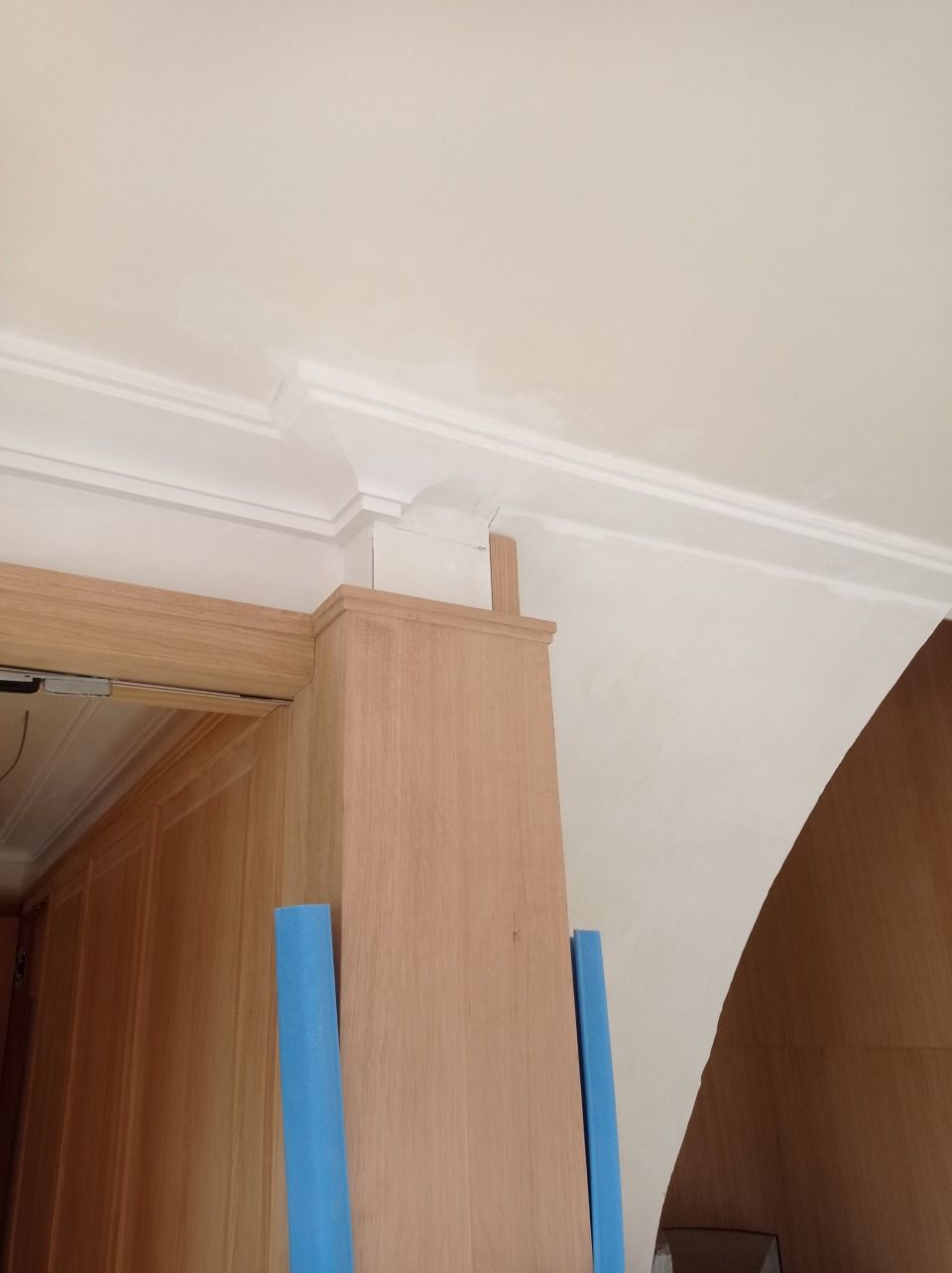 Eine Eckansicht eines Zimmers, die weisse Zierleisten an einem Holzpfosten zeigt.