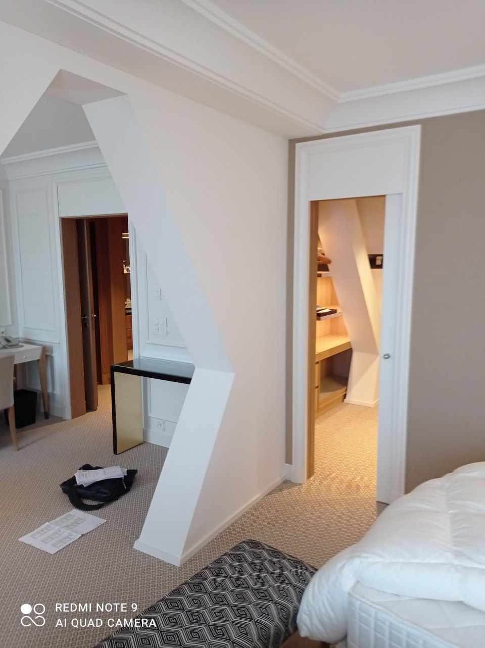 Ein Hotelzimmer mit cremefarbenen Wänden,Teppichboden, einem Bett und einem Schreibtisch, die zu einem Kleiderschrank führt.