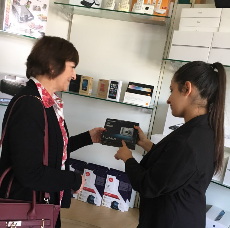 Élève en simulation de vente avec une cliente tenant un appareil photo numérique