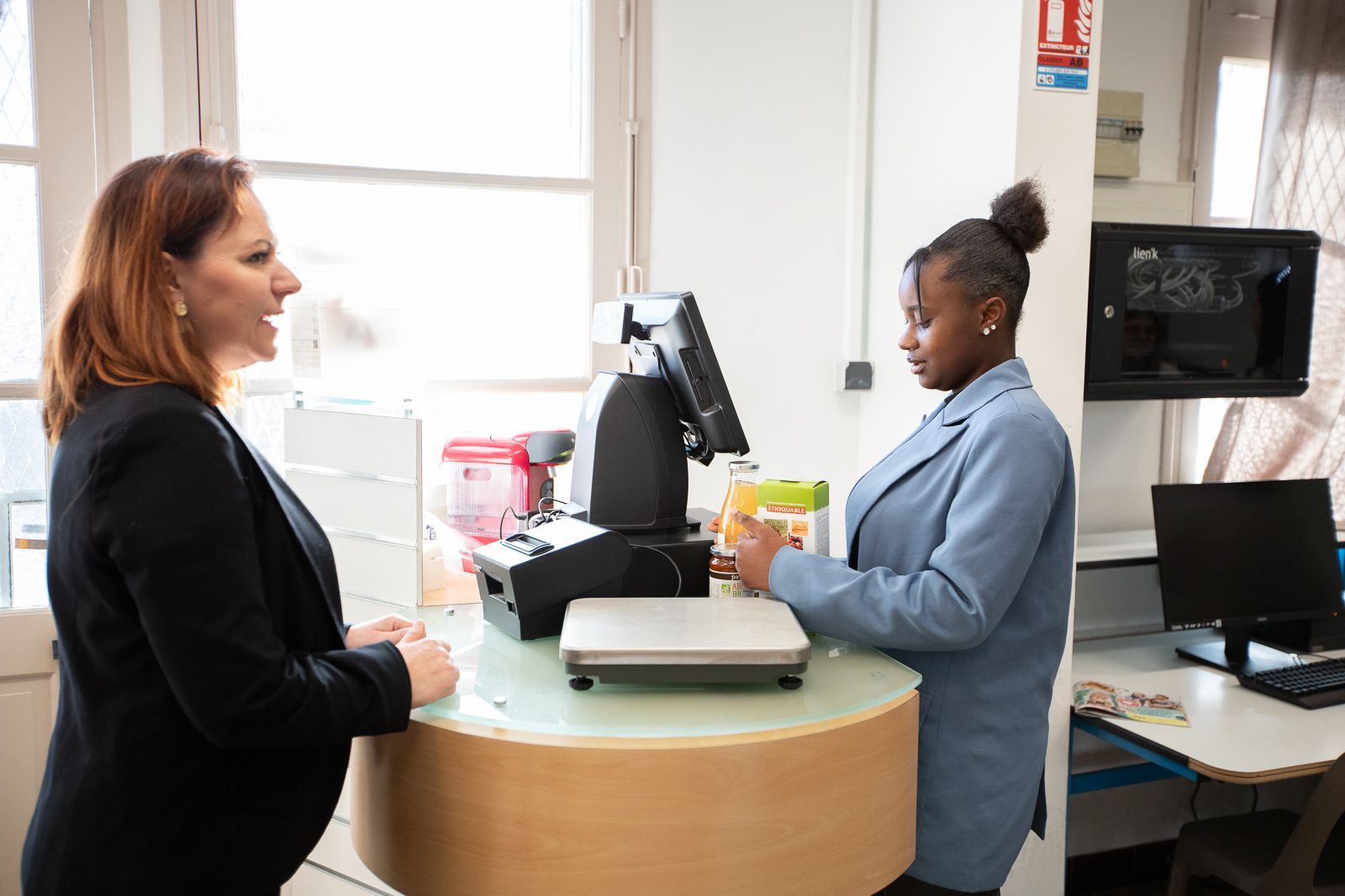 Élève en simulation de vente avec une cliente tenant un appareil photo numérique