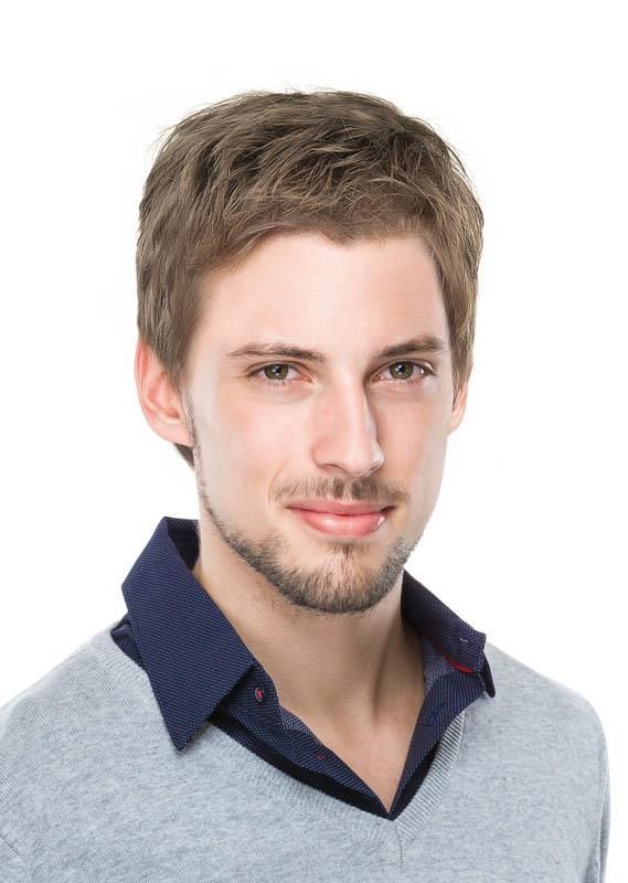 Ein Mann mit Bart trägt einen grauen Pullover und ein blaues Hemd