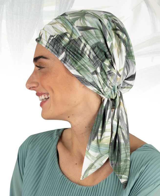 Eine Frau mit einem grün-weißen Kopftuch lächelt.