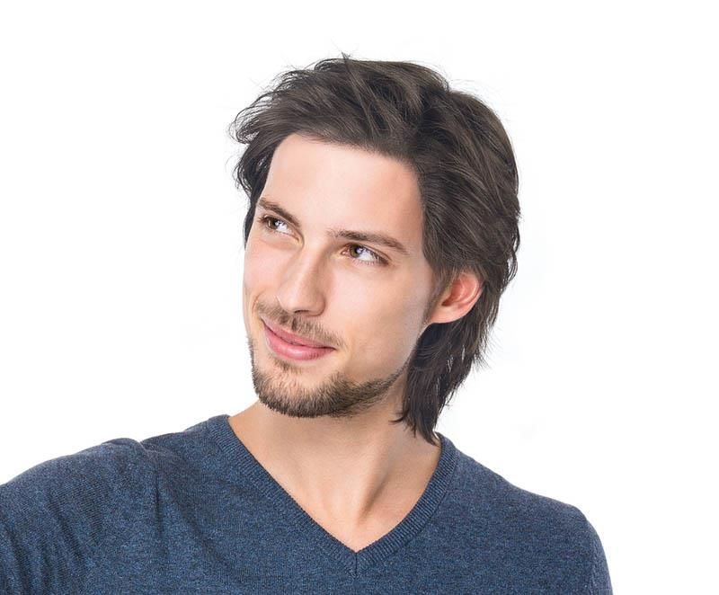 Ein Mann mit Bart trägt einen blauen Pullover und lächelt.