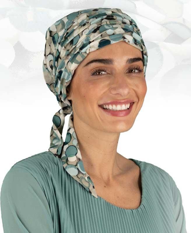 Eine Frau mit Turban und grünem Hemd lächelt