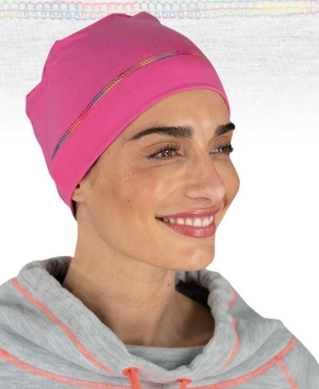 Eine Frau mit rosa Hut und grauem Sweatshirt lächelt