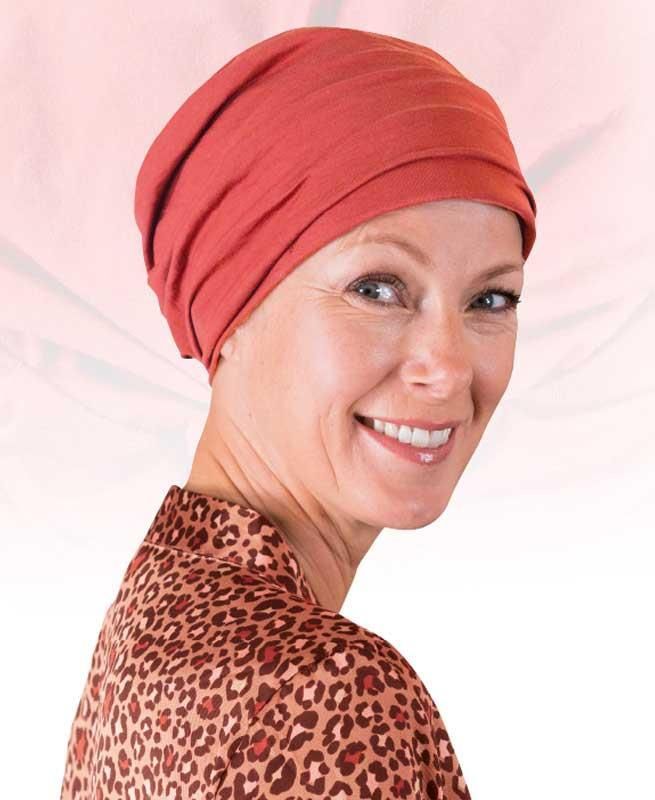 Eine Frau mit rotem Turban und Hemd mit Leopardenmuster lächelt