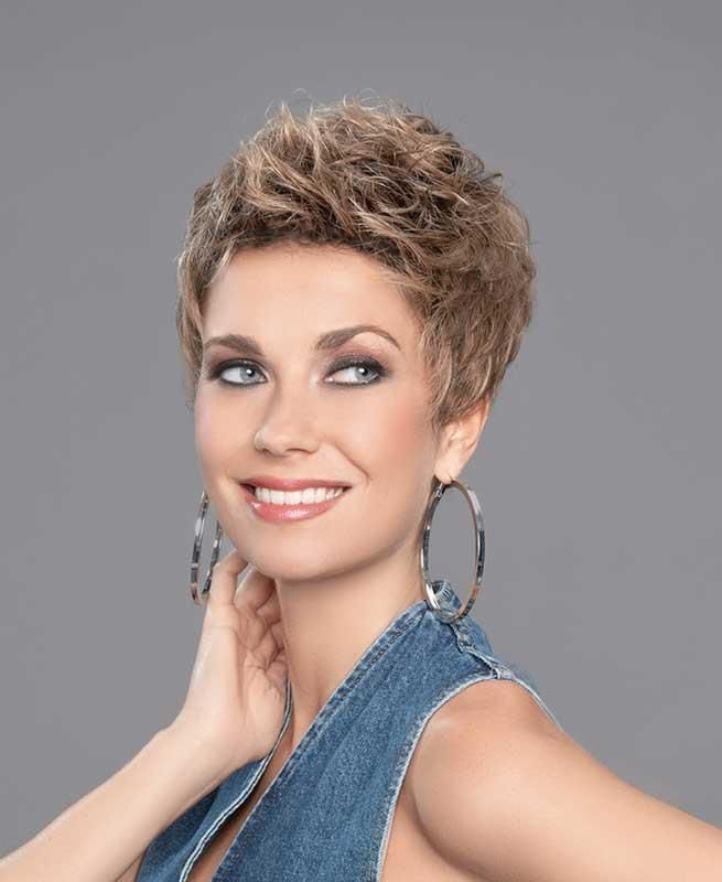 Eine Frau mit Perücke und Creolen lächelt.