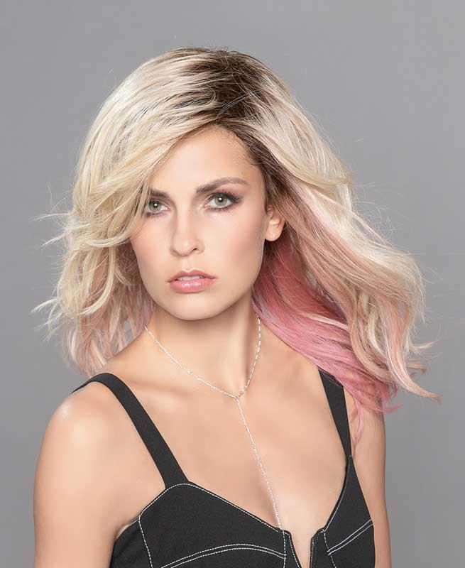 Eine Frau mit blondem und rosa Haar trägt ein schwarzes Tanktop und eine Halskette.