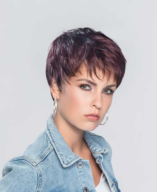 Eine Frau mit einer Kurzhaarperücke und Jeansjacke schaut in die Kamera.