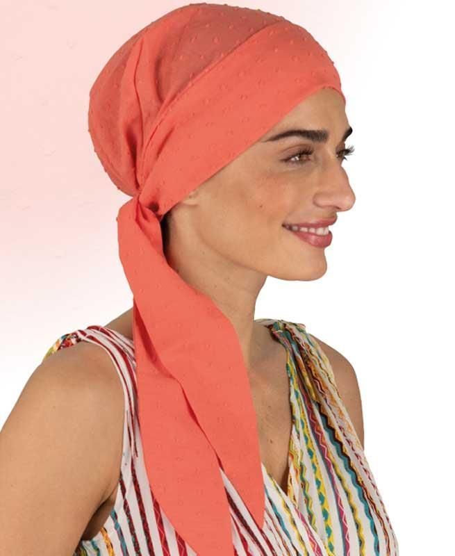 Eine Frau mit einem orangefarbenen Kopftuch lächelt