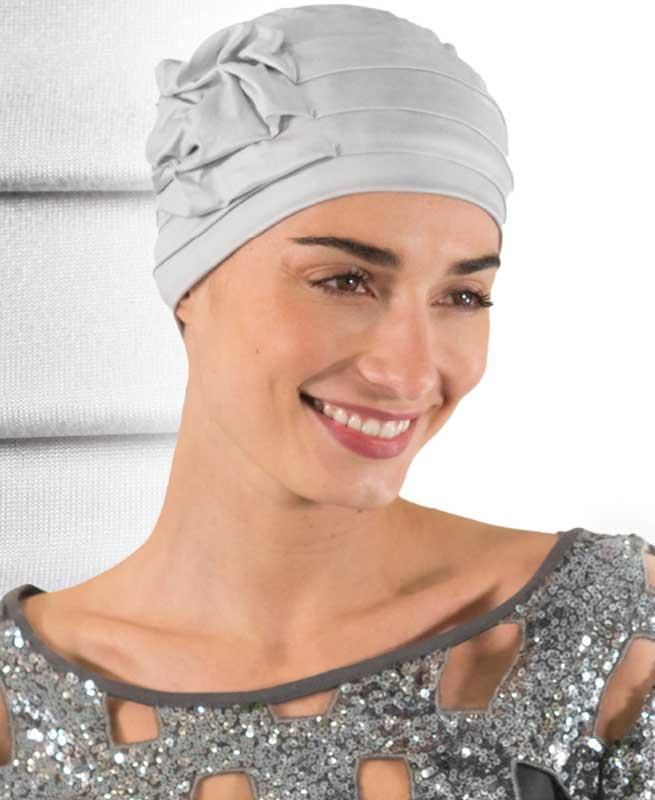 Eine Frau mit weißem Hut und silbernem Kleid lächelt