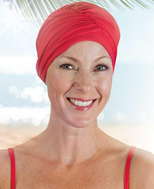 Eine Frau mit einem roten Turban lächelt in die Kamera