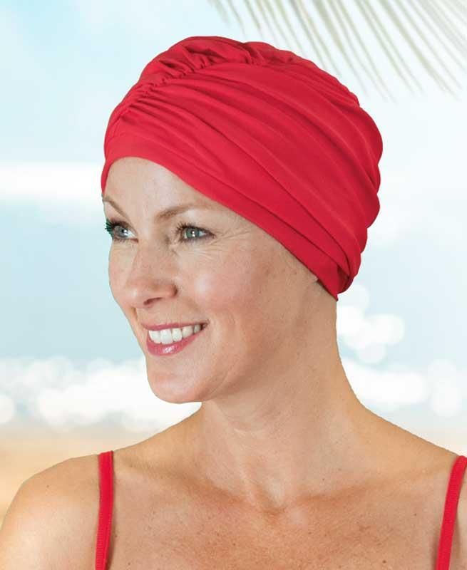 Eine Frau mit einem roten Turban lächelt am Strand