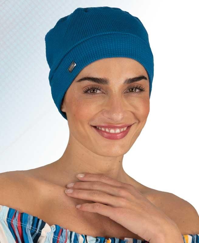 Eine Frau mit blauem Hut lächelt in die Kamera