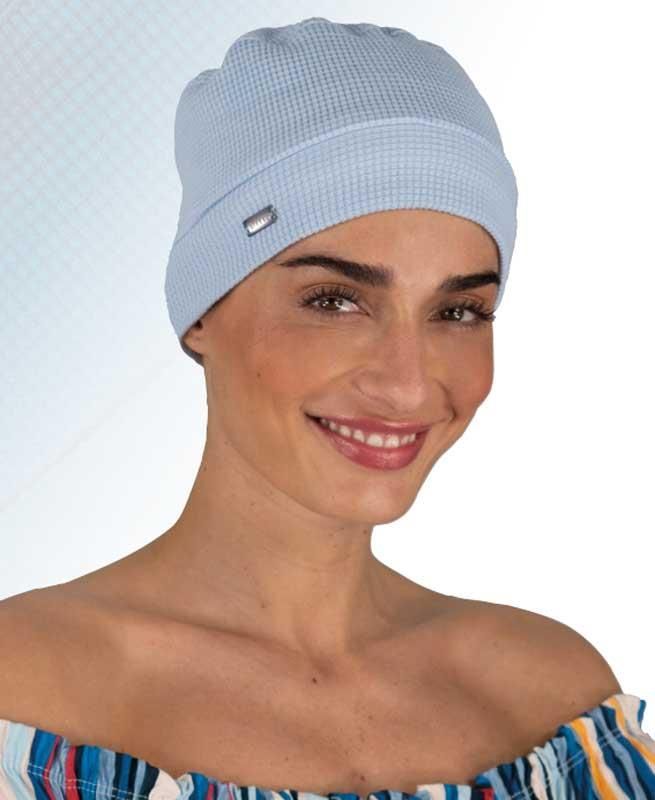 Eine Frau trägt eine hellblaue Mütze und lächelt.