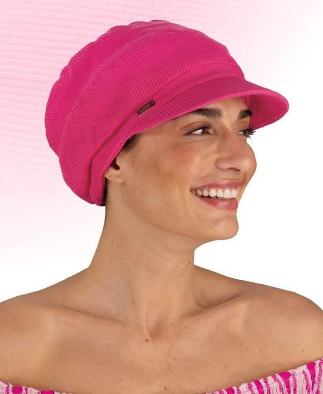 Eine Frau trägt einen rosa Hut und lächelt