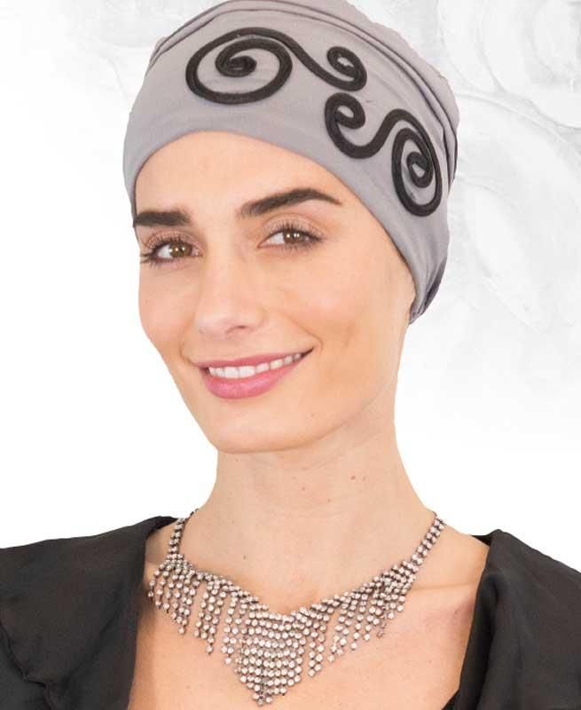 Eine Frau mit Hut und Halskette lächelt