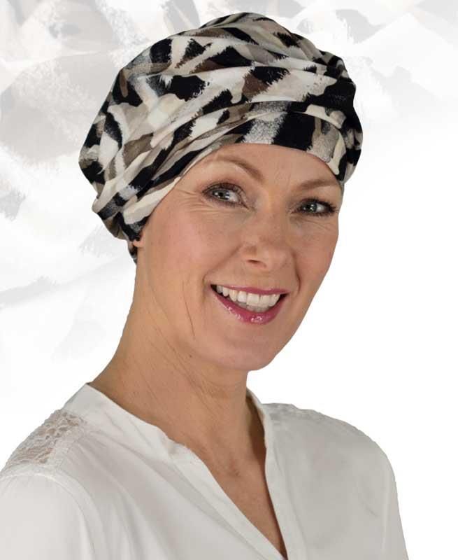 Eine Frau mit Turban und weißem Hemd lächelt.