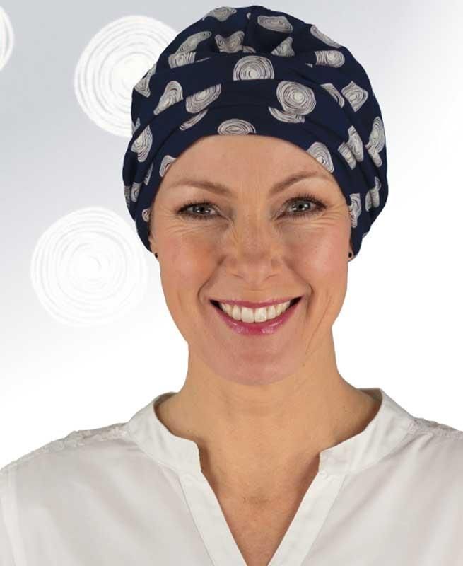 Eine Frau mit blauem Hut und weißem Hemd lächelt