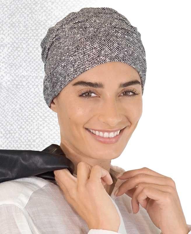 Eine Frau mit grauem Hut und schwarzer Krawatte lächelt.