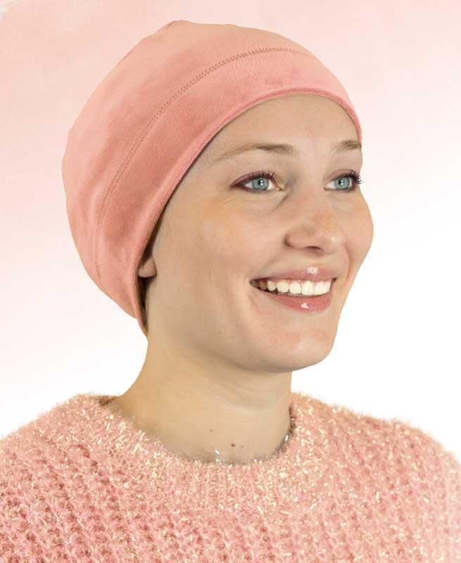 Eine Frau mit einer rosa Mütze und einem rosa Pullover lächelt.
