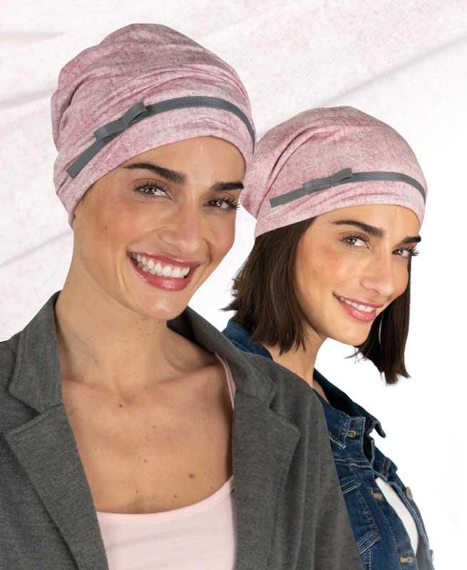 Zwei Frauen tragen rosa Hüte und lächeln in die Kamera