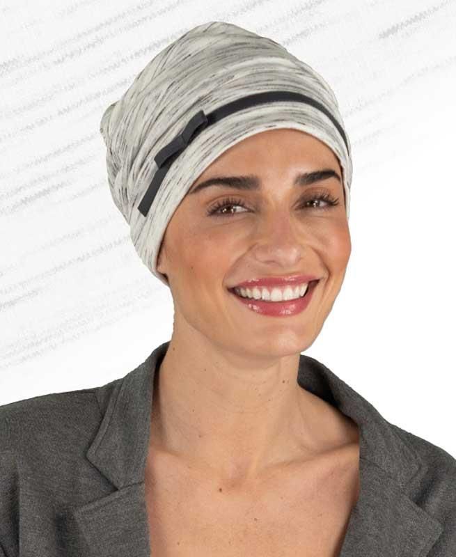 Eine Frau mit Turban und grauer Jacke lächelt