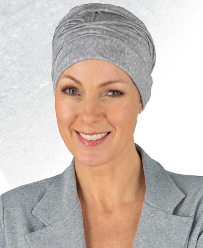 Eine Frau mit grauem Hut und grauer Jacke lächelt.