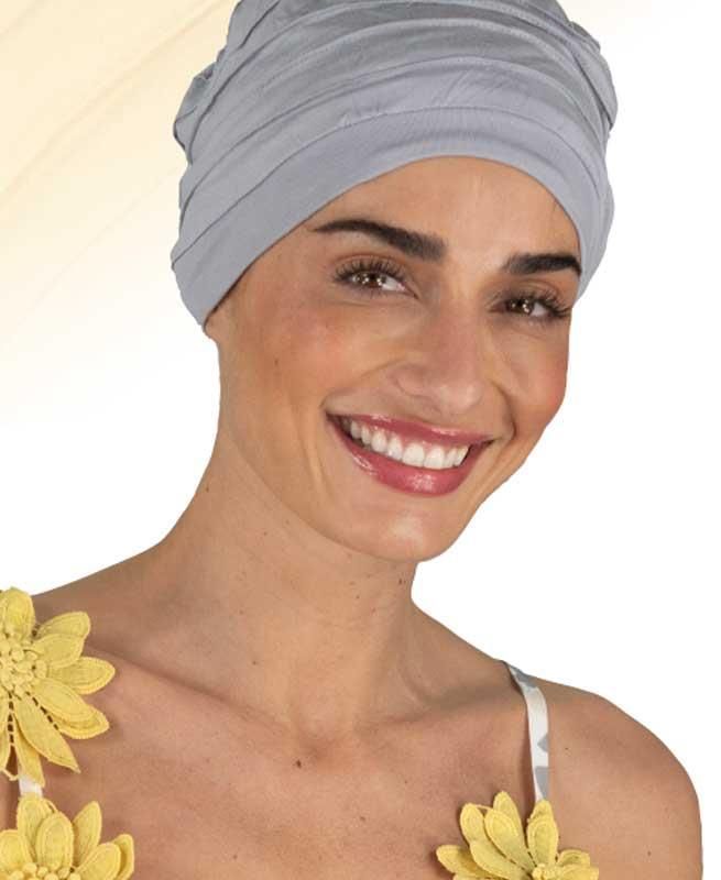 Eine Frau mit einem grauen Turban lächelt und hat gelbe Blumen um den Hals