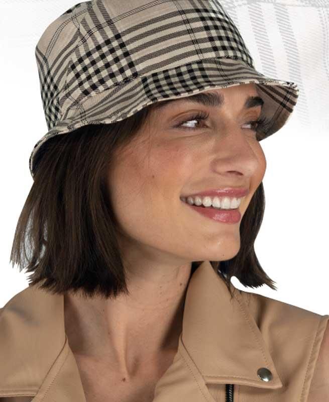 Eine Frau trägt einen karierten Hut und lächelt