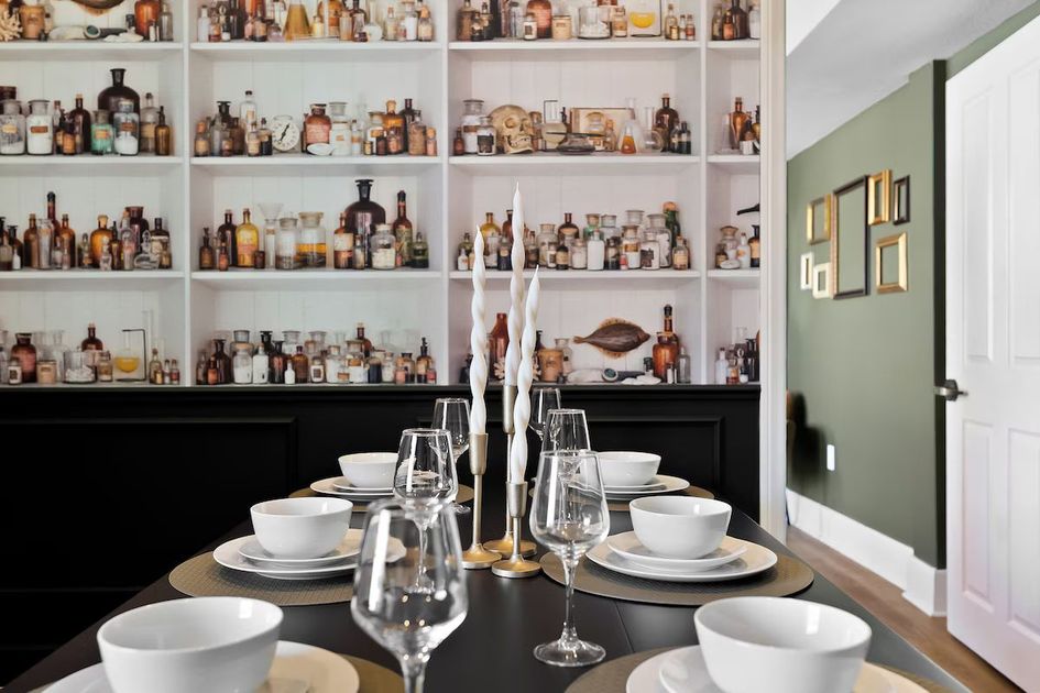 Elegant dining table set in front of wall shelves filled with decorative bottles and glassware