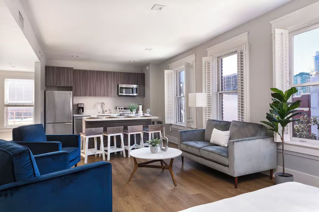 Modern living room with gray sofa, black coffee table, wood floor, and large paneled wall decor