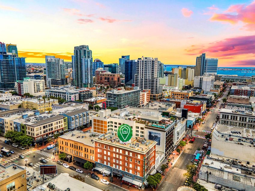 Aerial view of a downtown skyline at sunset with colorful high-rises and busy streets below