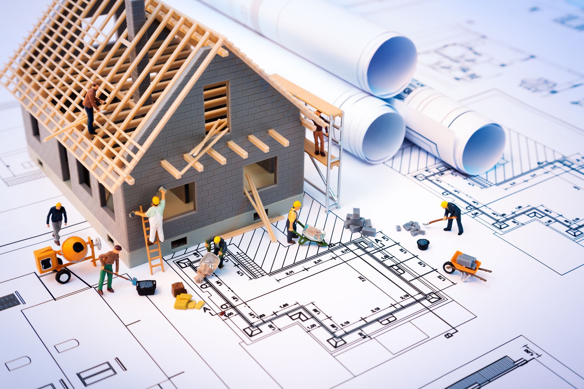 Représentation des travaux de construction avec une maquette de maison posée sur un plan de travail