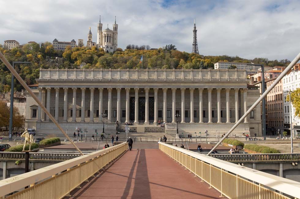 Vue depuis un pont en direction d’un majestueux bâtiment à colonnades et d’une cathédrale sur une colline, dans un paysage urbain
