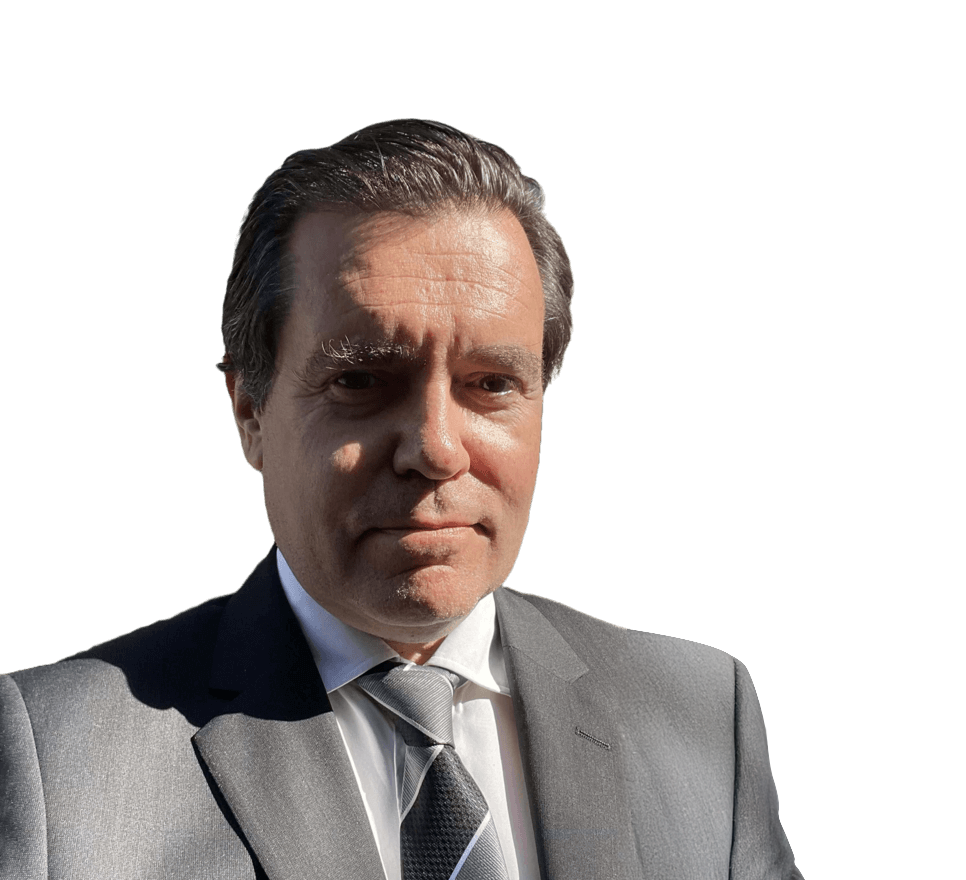 Maître Gimalac en costume gris et cravate sur fond blanc uni, regardant l’objectif.