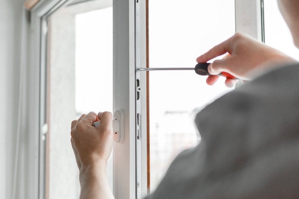 Homme avec un tournevis réparant une fenêtre