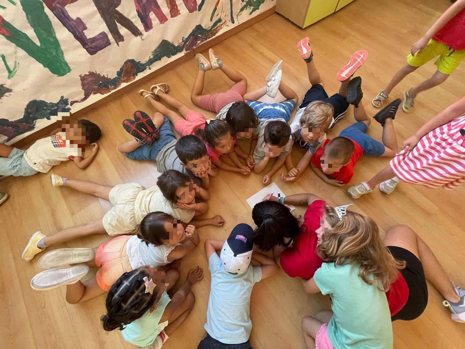 Un grupo de niños están acostados en el suelo formando un círculo.
