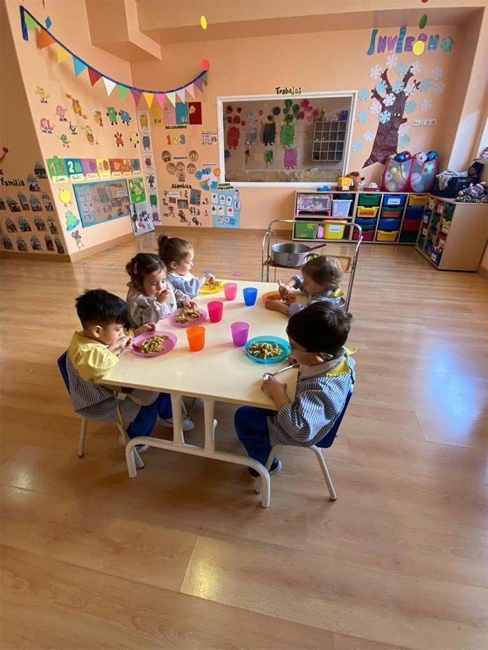 Un grupo de niños está sentado en una mesa comiendo comida.
