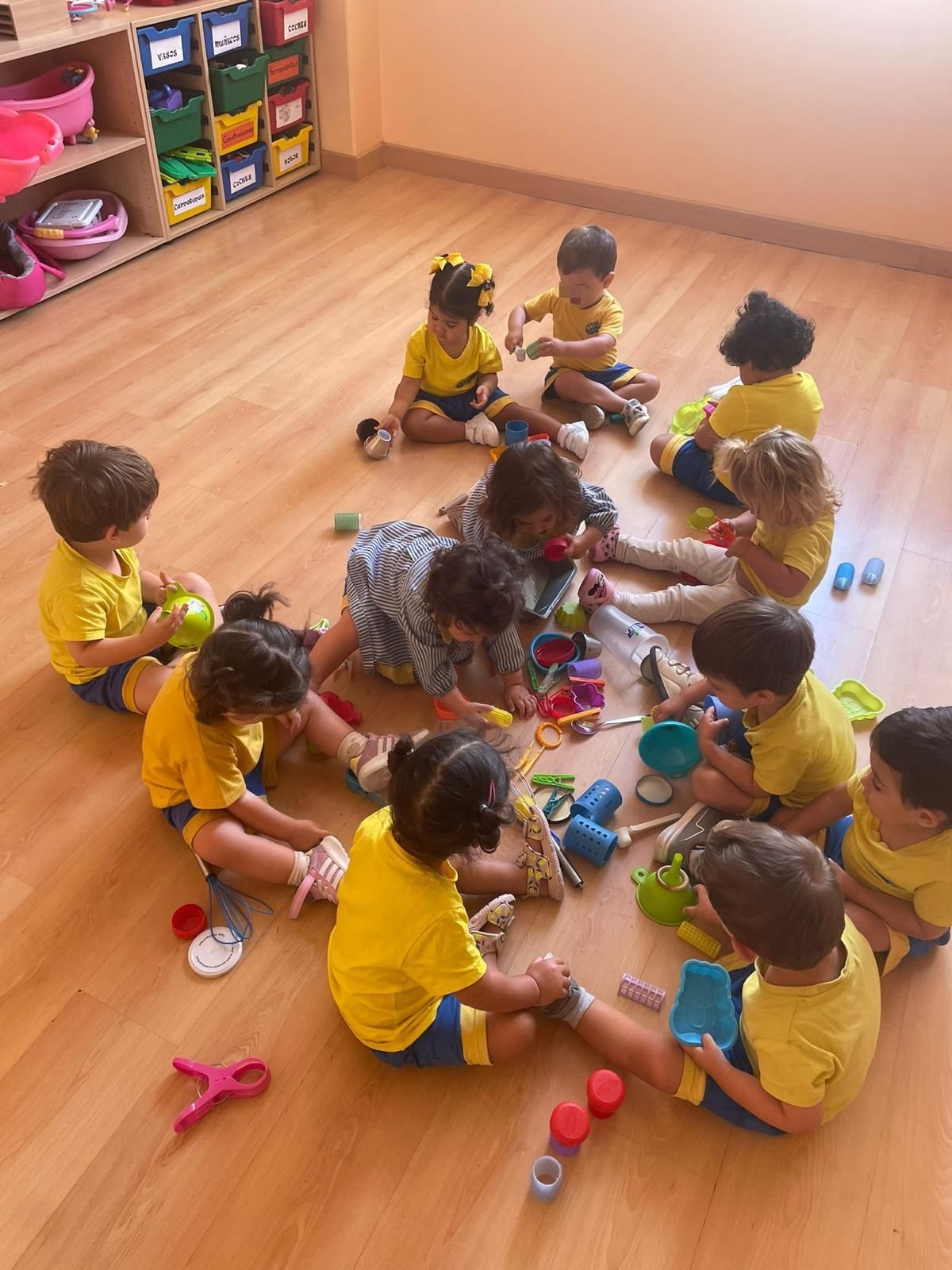 Un grupo de niños está sentado en el suelo frente a una pared azul.