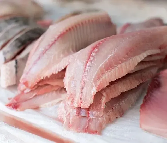 Un primer plano de una pila de pescado cortado en rodajas sobre una mesa.