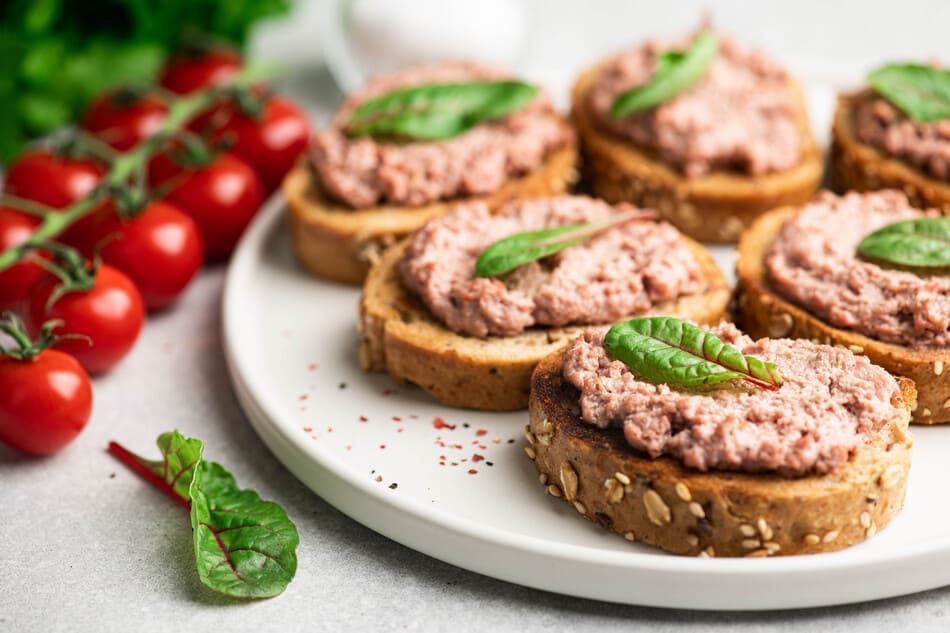 Un plato blanco cubierto de sándwiches rellenos de carne y tomates.