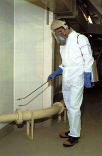 Un hombre con un traje blanco está rociando algo en una tubería.