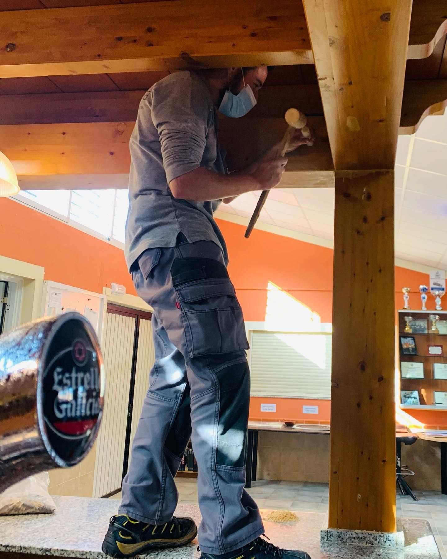 Un hombre con una máscara está martillando un poste de madera.