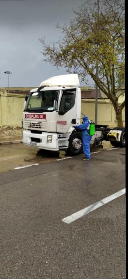 Un hombre con traje de protección está rociando un camión.