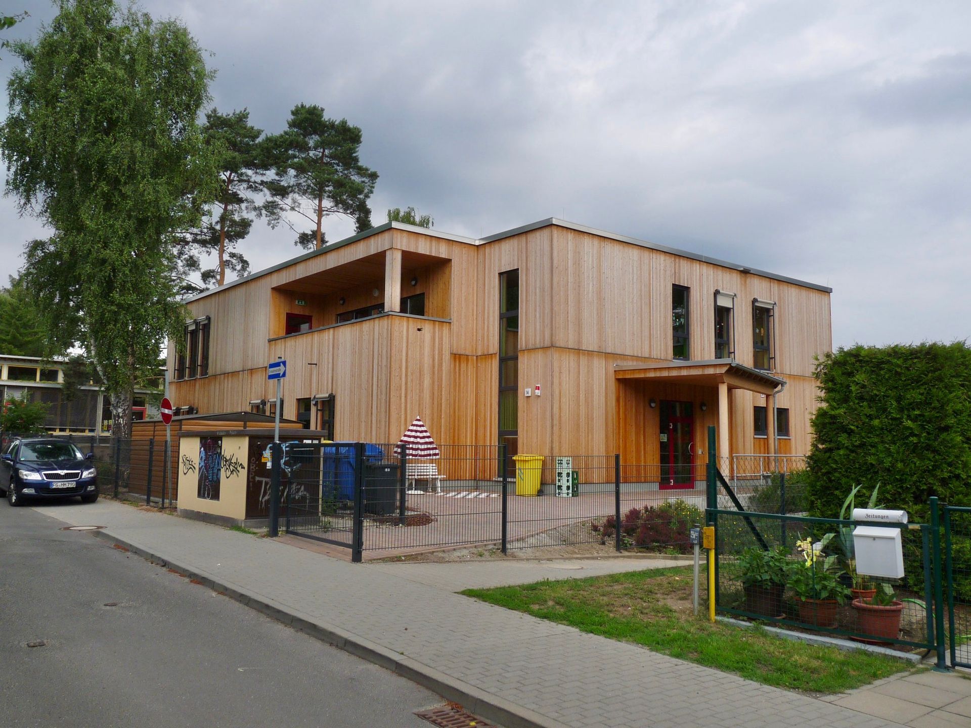 Zweigeschossiges Bildungsgebäude in Holzbauweise mit überdachtem Eingangsbereich.