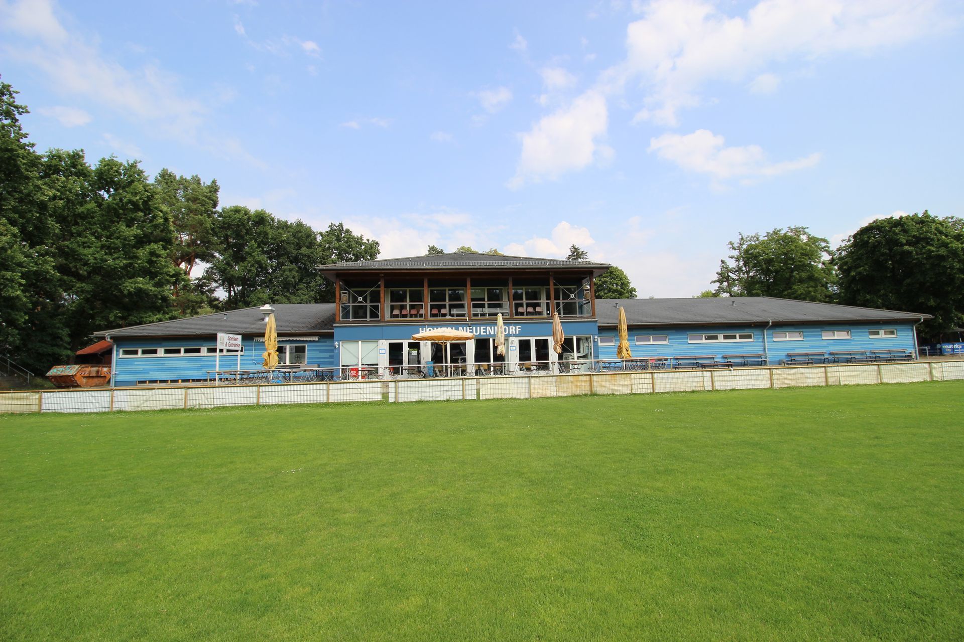 Sportfunktionsgebäude mit großem Vorplatz und angrenzender Grünfläche.